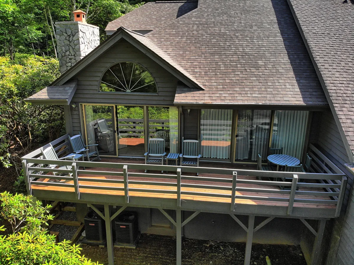 The tranquil wooden deck of Penrith Hideaway, framed by lush greenery and outfitted with comfortable outdoor furniture. Large windows and a stone chimney hint at the cozy retreat inside, while the deck offers a peaceful spot to unwind after outdoor adventures.