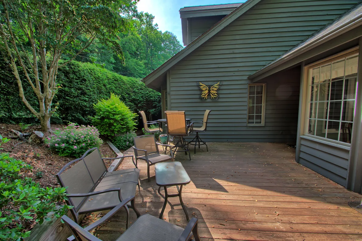 A tranquil shot of the home's wooden deck, complete with comfortable seating and butterfly wall art. The surrounding greenery and open space invite moments of laughter, outdoor dining, and peaceful stargazing—ideal for family relaxation.