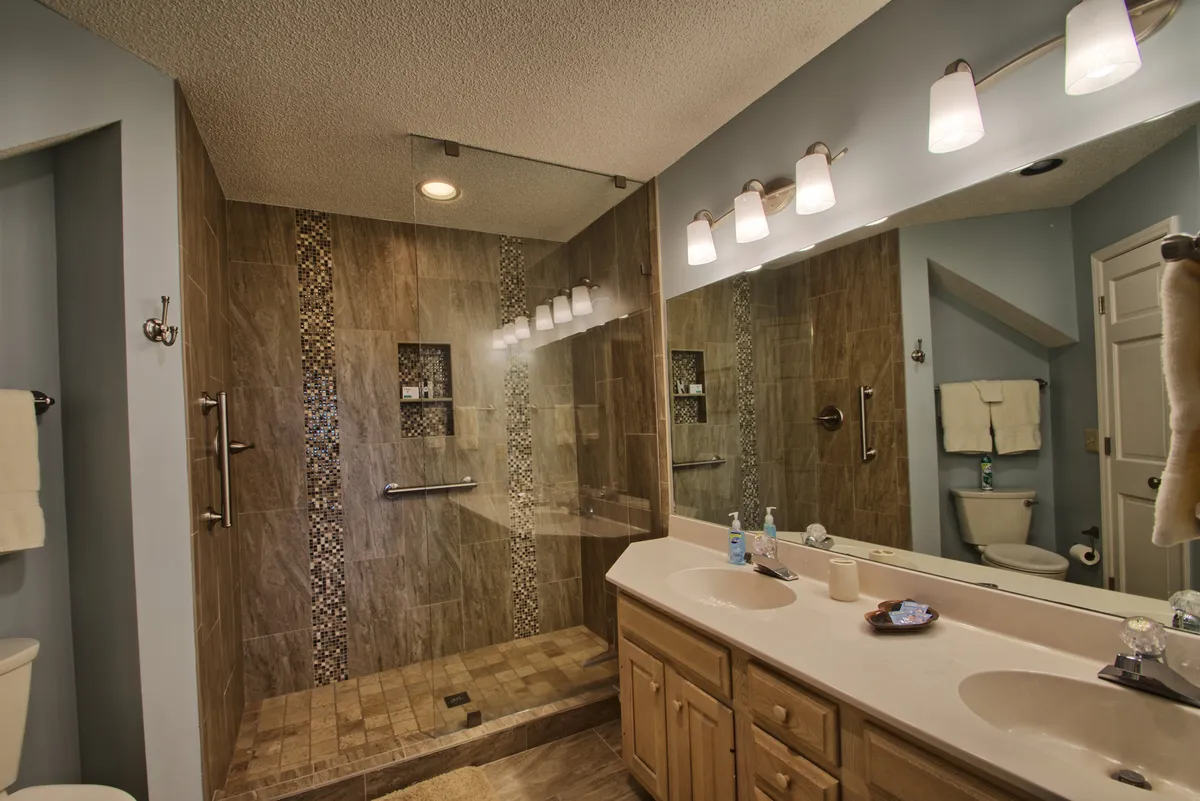 A stylish, modern bathroom featuring double vanity sinks, a glass shower enclosure, and decorative tiling. The space feels inviting and spa-like, perfect for winding down after a day of activities.