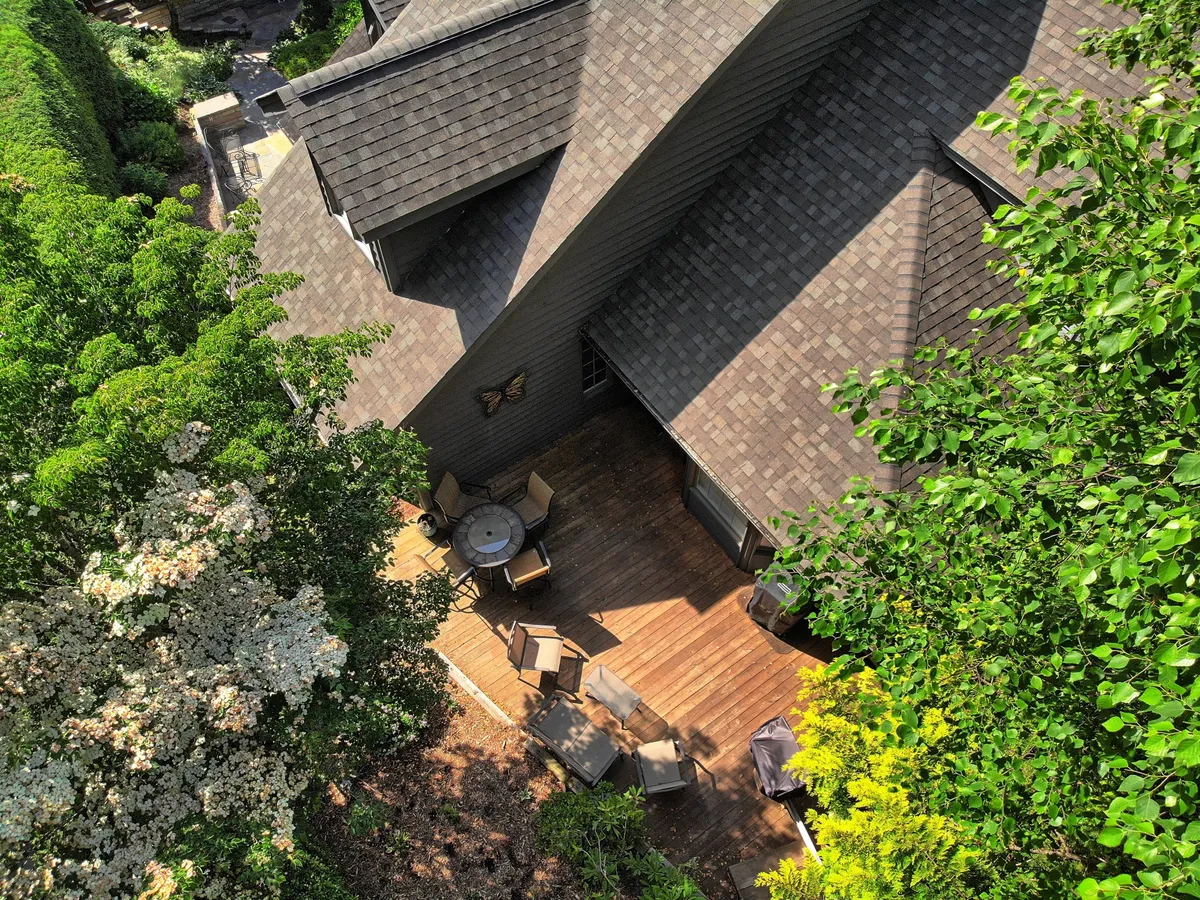 A spacious deck area surrounded by vibrant greenery, featuring outdoor furniture ideal for dining or relaxing. The setting is serene and inviting, perfect for enjoying a morning coffee or a sunset dinner while soaking in the sounds and sights of nature.